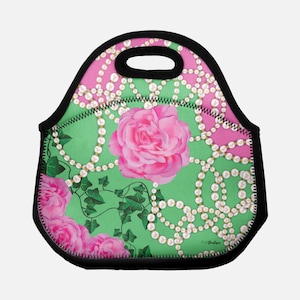 May include: A green and pink lunch bag with a floral and pearl design. The bag has a black handle and a zipper closure.