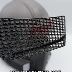 May include: Close-up of a black mesh visor with the text "RAW PRINT MESH VISOR" and "MESH VISOR PROVIDES GREAT VISIBILITY AND BREATHABILITY". The visor is attached to a dark gray helmet.