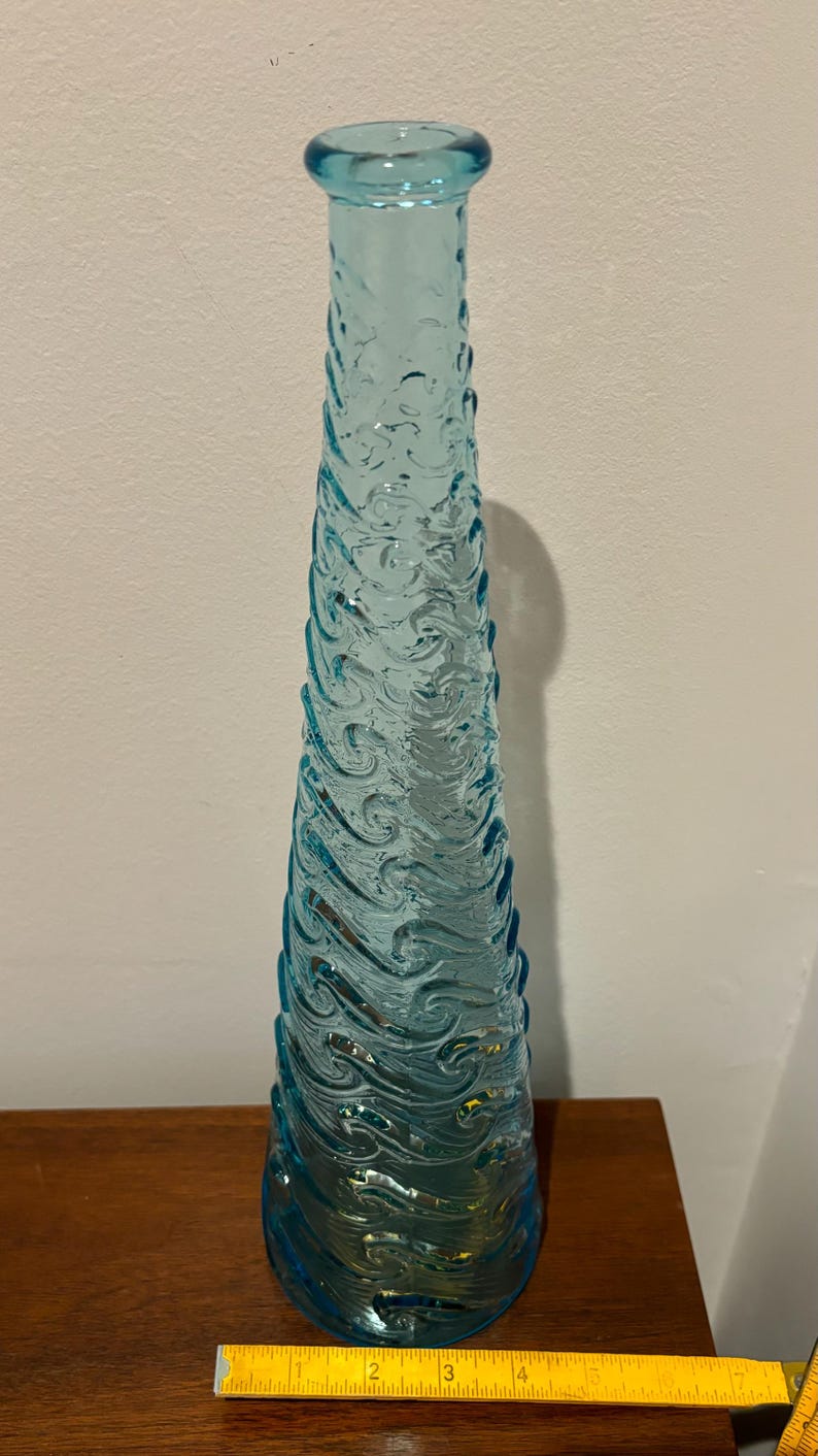 May include: A tall, light blue glass vase with a wavy, textured design. The vase is approximately 12 inches tall.