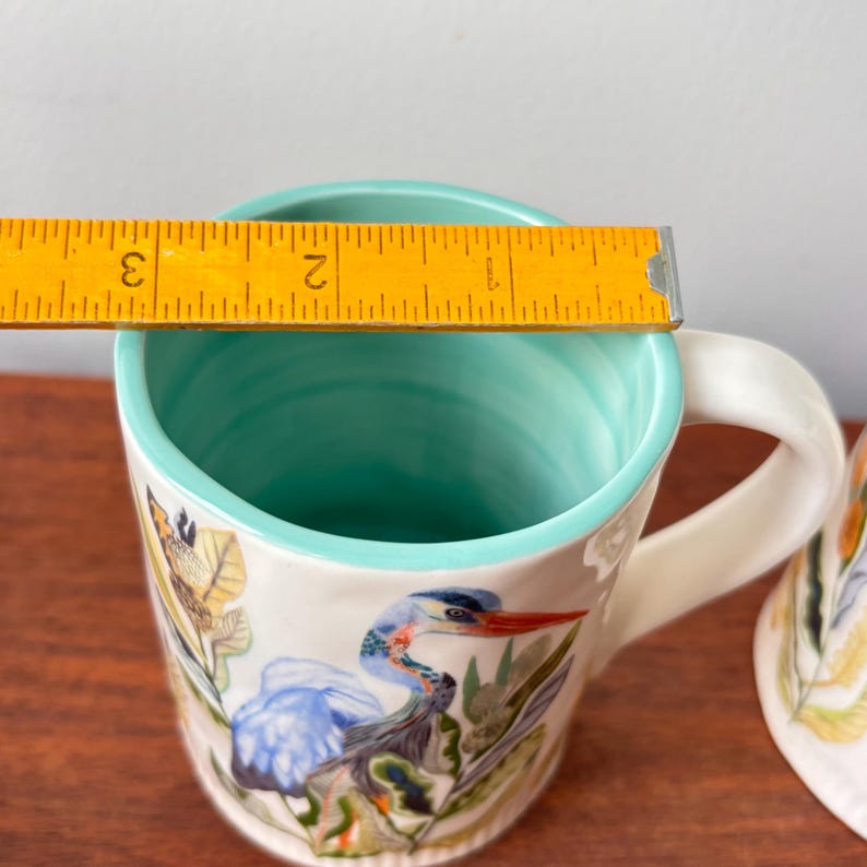 Puede incluir: Taza de cer&aacute;mica blanca con un dise&ntilde;o de garza azul. La taza tiene un asa blanca y un interior turquesa. La taza tiene aproximadamente 7,6 cm de di&aacute;metro.