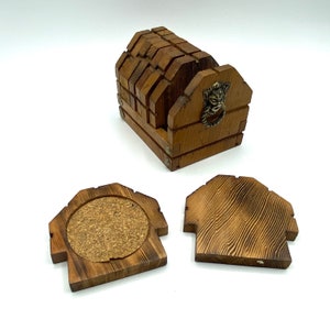 May include: Wooden coaster set with six coasters and a holder. The holder is shaped like a small house with a lion head knocker. The coasters are made of wood with a cork insert.