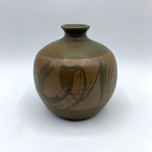 May include: A small, round, brown ceramic vase with a light brown glaze and abstract design.