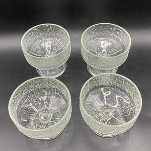 May include: Set of four clear glass dessert bowls with a textured, crackled surface. Each bowl has a short, round stem.