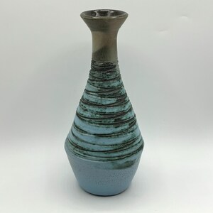 May include: A blue and brown ceramic vase with a textured, striped design. The vase has a narrow neck and a wide base.