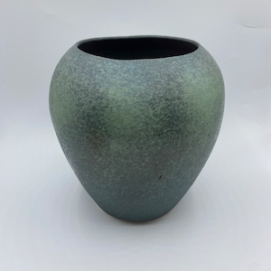 May include: A dark green ceramic vase with a textured surface. The vase has a rounded shape and a wide opening.