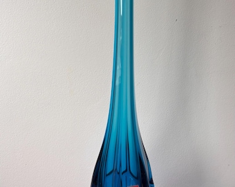 Pode incluir: Um vaso alto de vidro azul vibrante com uma base alargada e um corpo esguio e alongado. O vaso tem uma forma orgânica única com uma superfície texturizada e um topo alargado. O vaso tem cerca de 38 cm de altura.