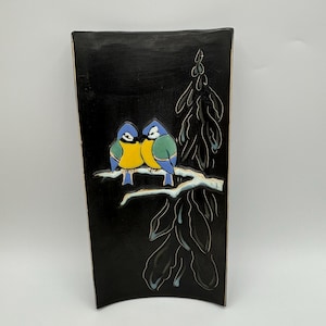 May include: A black ceramic rectangular plate with a raised design of two blue birds with yellow bellies perched on a branch with a tree behind them.