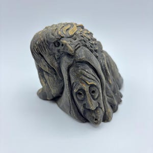 Könnte beinhalten: Eine kleine, handgeschnitzte Skulptur einer Frau mit einem Vogel auf dem Kopf. Die Skulptur ist aus dunkelbraunem Material gefertigt und hat einen rustikalen, antiken Look.