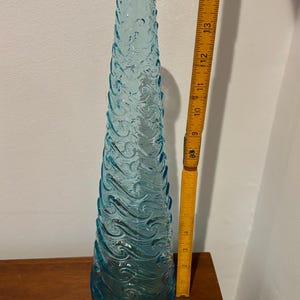 May include: A tall, light blue glass vase with a textured, wave-like design. The vase is approximately 15 inches tall.