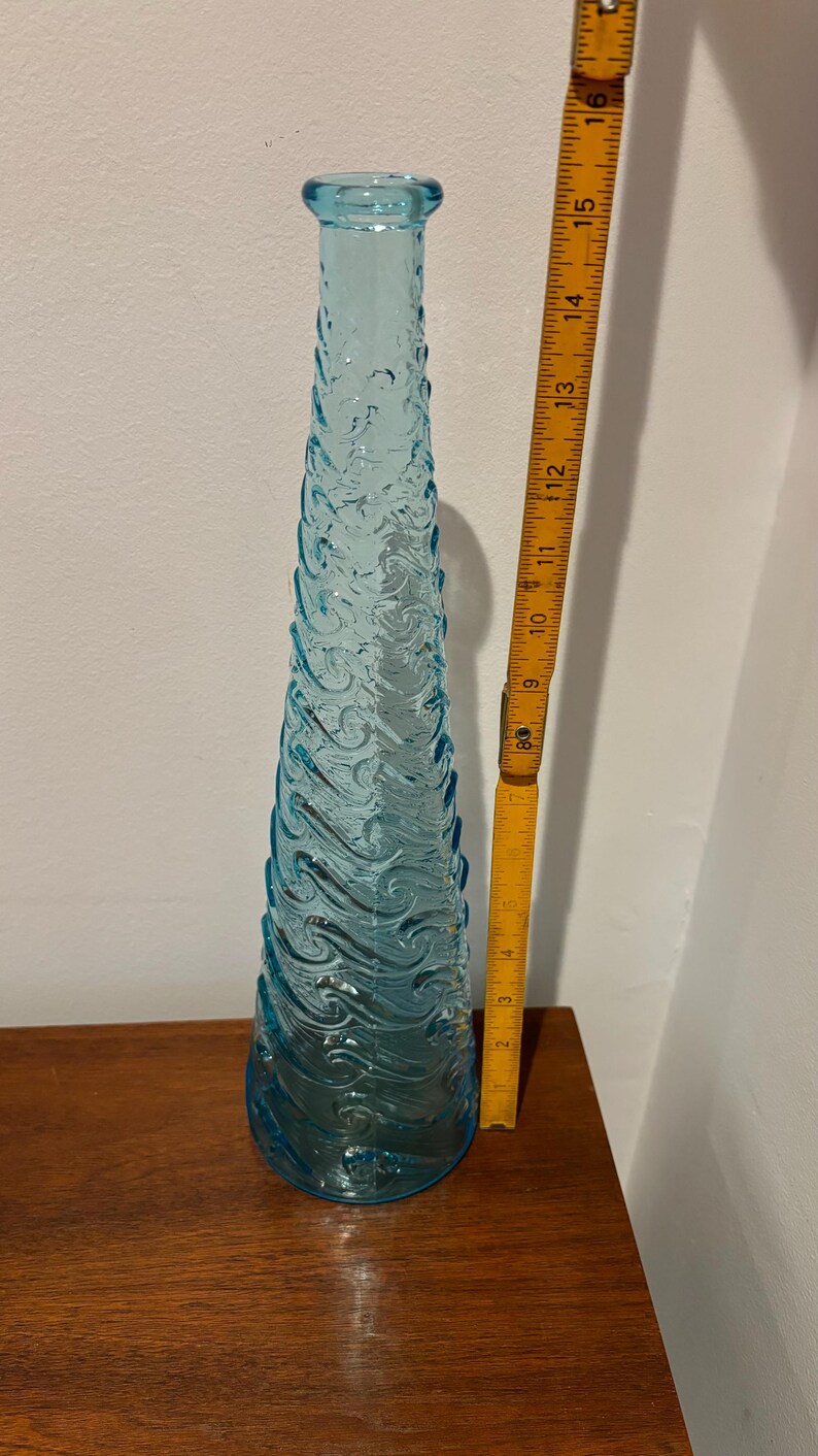 May include: A tall, light blue glass vase with a textured, wave-like design. The vase is approximately 15 inches tall.