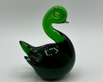 May include: A green glass swan figurine with a rounded body and a long, curved neck.