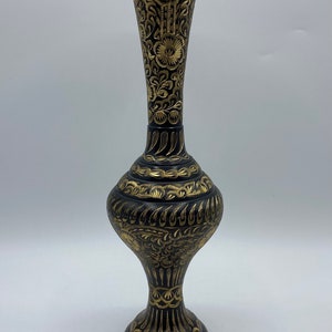 Puede incluir: Un jarrón negro con diseños florales dorados. El jarrón tiene una base ancha y un cuello estrecho.