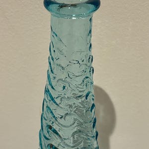 May include: A tall, clear blue glass vase with a wavy, textured design.