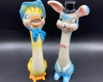 May include: A pair of vintage ceramic salt and pepper shakers. The salt shaker is shaped like a duck with a blue bonnet and a yellow body. The pepper shaker is shaped like a rabbit with a blue body and a black top hat.