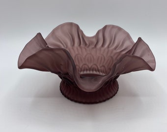 May include: A purple glass bowl with a ruffled edge and a textured base.