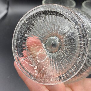 May include: Close-up of the bottom of a clear glass drinking glass with a textured, rippled design.