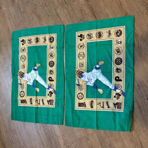 May include: Two green pillowcases with a baseball player in a white uniform throwing a ball. The pillowcases have a gold border with baseball team logos around the edge.