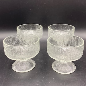 May include: Set of four clear glass dessert bowls with a textured surface and a pedestal base.