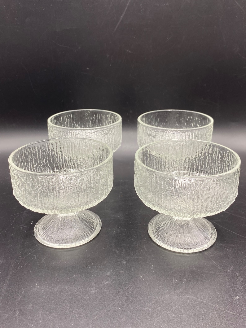 May include: Set of four clear glass dessert bowls with a textured surface and a pedestal base.