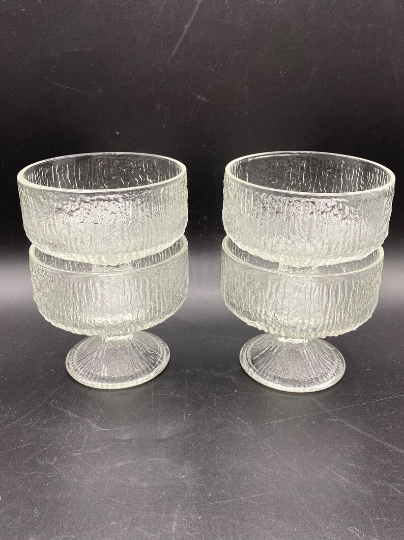 May include: Set of four clear glass dessert bowls with a textured, frosted finish. Each bowl has a pedestal base.