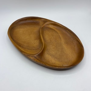 May include: A wooden serving tray with three divided sections. The tray is oval shaped and has a natural wood finish.