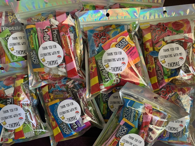 Pu&ograve; includere: Diversi sacchetti di plastica trasparenti pieni di caramelle colorate e piccoli giocattoli. Ogni sacchetto ha un adesivo rotondo con un personaggio dei cartoni animati e il testo "Grazie per aver festeggiato con me! -Thomas".