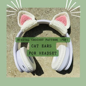 Könnte beinhalten: Weiße Häkelkatzenohren für ein Headset. Die Ohren sind innen rosa und außen weiß. Der Text "DIGITAL CROCHET PATTERN (PDF) CAT EARS FOR HEADSET" befindet sich auf dem Bild.