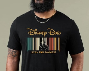 Puede incluir: Camiseta negra con un gráfico dorado del texto "Disney Dad" y un código de barras con una silueta del castillo de Disney y Mickey Mouse. El texto del código de barras dice "Scan for Payment."