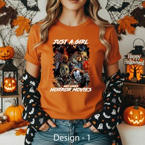 May include: An orange t-shirt featuring a graphic print of various horror movie characters and the white text "JUST A GIRL WHO LOVES HORROR MOVIES". The design includes illustrations of figures like Michael Myers, Chucky, and Pennywise.