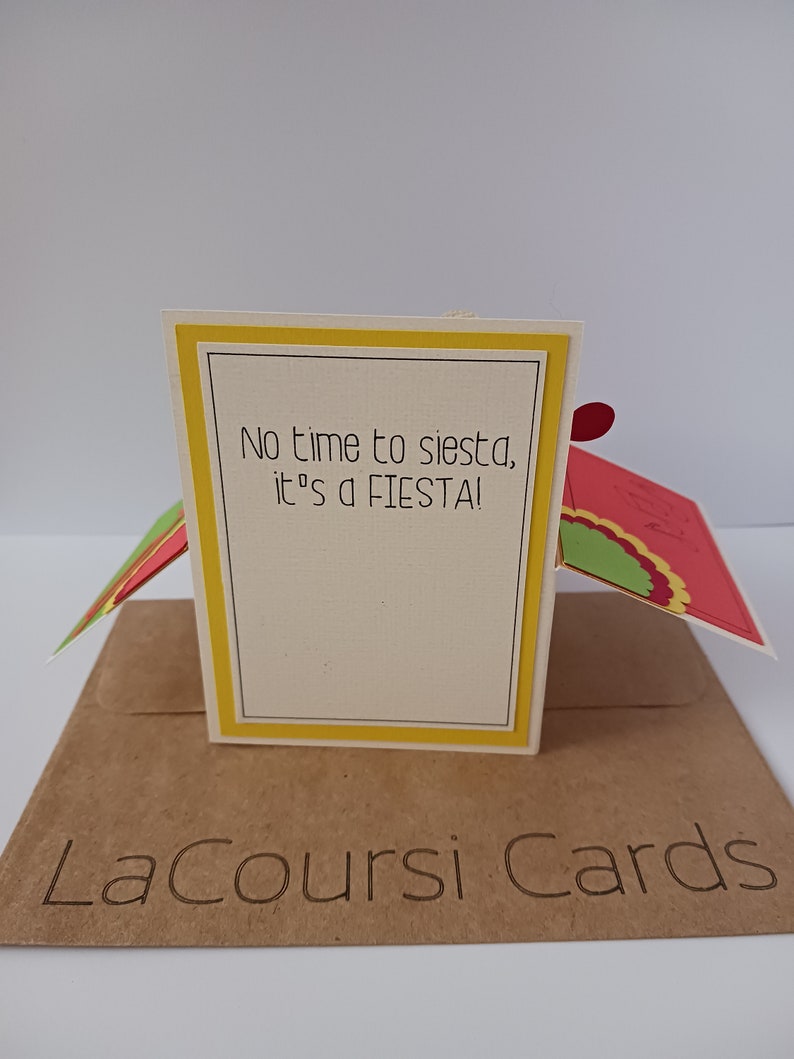 May include: A yellow and white card with the text "No time to siesta, it's a FIESTA!" on the front. The card is folded in half and has a brown envelope with the text "LaCoursi Cards" on the front.