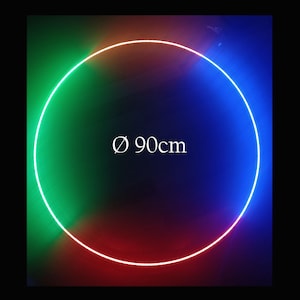 以下が含まれることがあります： 直径90cmの光るネオンリング。リングは緑から赤、青へと変化するグラデーションで照らされています。「Ø 90cm」の文字がリングの中央に配置されています。