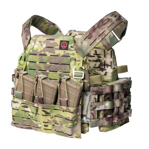 May include: A tactical vest with a camouflage pattern, featuring multiple pouches and straps. The vest has a red logo on the front and is equipped with magazine holders.