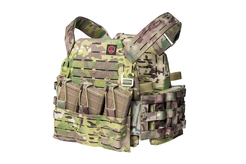 May include: A tactical vest with a camouflage pattern, featuring multiple pouches and straps. The vest has a red logo on the front and is equipped with magazine holders.
