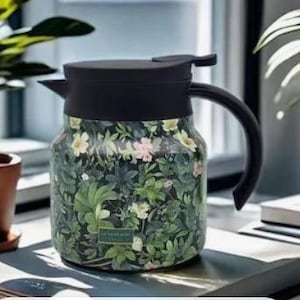 May include: A black and floral insulated carafe with a handle and a spout. The carafe features a botanical design with green leaves and small pink and white flowers. The lid and handle are black.