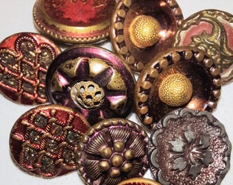Puede incluir: Surtido de diez botones vintage en varios colores y diseños, incluyendo rojo, dorado y plateado. Los botones presentan patrones y texturas intrincados, como motivos florales, formas geométricas y un centro elevado.
