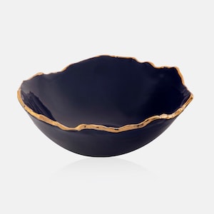 May include: A dark blue ceramic bowl with an irregular, organic shape. The rim is trimmed with a gold metallic finish, adding a touch of elegance. This decorative bowl is ideal for serving or as a stylish accent piece.