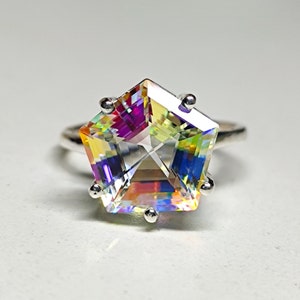 May include: A silver ring with a large, faceted, iridescent gemstone in the shape of a star. The gemstone has a rainbow of colors, including yellow, green, blue, and purple.