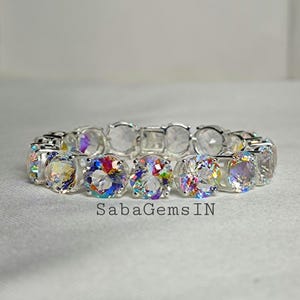 May include: A silver bracelet with a row of iridescent round gemstones. The bracelet is made of a silver chain with a clasp.