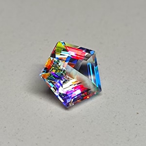 May include: A square-cut gemstone with a vibrant display of colors, including red, blue, yellow, and green. The facets of the gem reflect light, creating a rainbow effect. The gemstone is set against a neutral gray background.