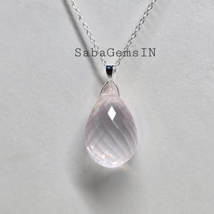 May include: A silver chain necklace with a pink rose quartz pendant. The pendant is faceted and has a teardrop shape.
