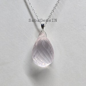 May include: A silver chain necklace with a pink rose quartz pendant. The pendant is faceted and has a teardrop shape.