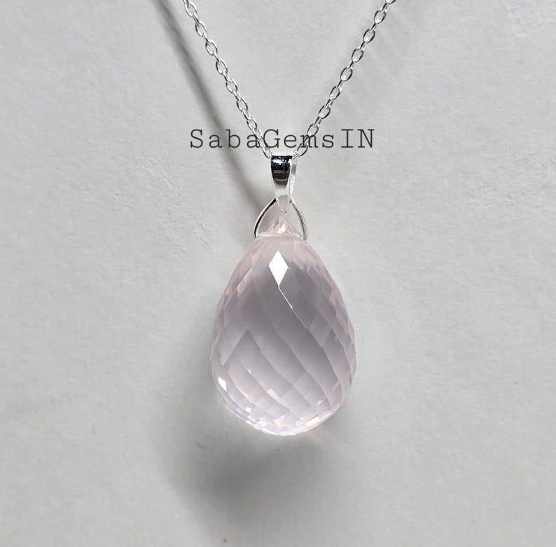 May include: A silver chain necklace with a pink rose quartz pendant. The pendant is faceted and has a teardrop shape.