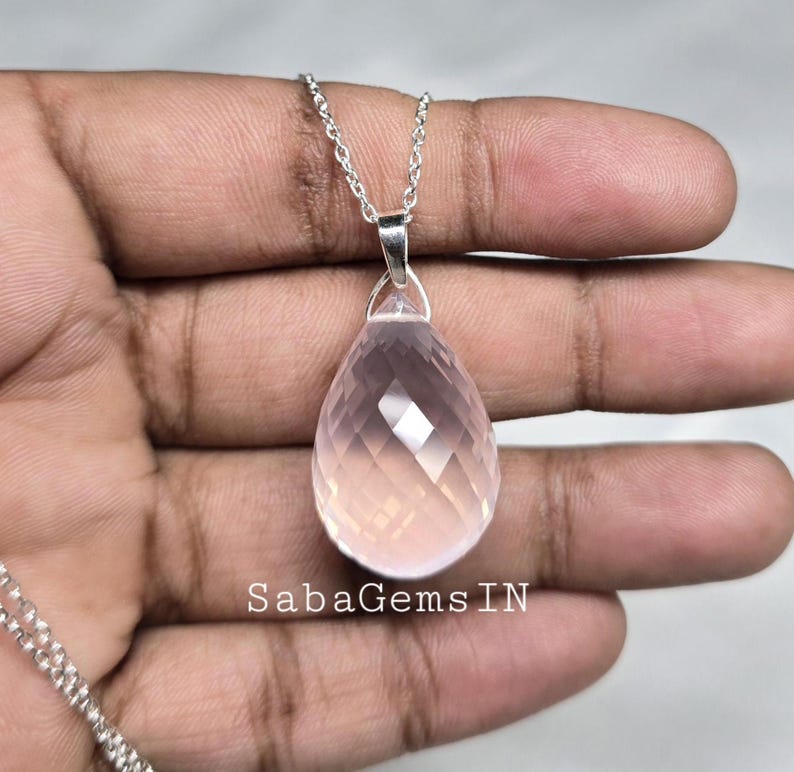 May include: A delicate silver chain necklace with a faceted pink quartz teardrop pendant. The pendant is approximately 1 inch in length and has a polished finish.