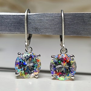 May include: A pair of silver dangle earrings with iridescent round gemstones. The gemstones have a rainbow of colors, including red, orange, yellow, green, blue, and purple.