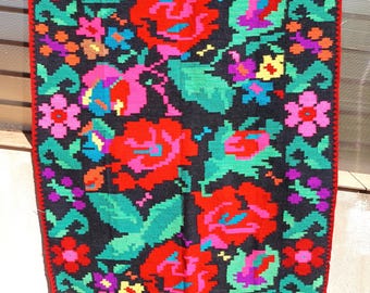 May include: A traditional Romanian handwoven rug with a black background and a colorful floral pattern. The rug features red, pink, green, yellow, and blue flowers.