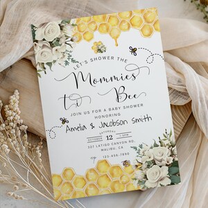 May include: Baby shower invitation with a bee theme. The invitation features a honeycomb design, floral accents, and the text "Let's Shower the Mommies to Bee." The invitation includes the names Amelia & Jacobson Smith, date, time, and location.
