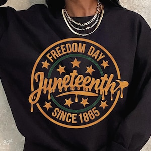 May include: Black sweatshirt with a gold circle graphic that says "Freedom Day Juneteenth Since 1865" with green stars and a dripping gold font.