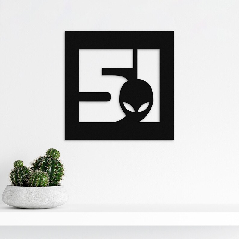 A metal sign depicting the number 51 and a head of a stylised alien, square shape and black colour.