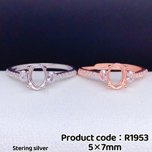 May include: Two sterling silver rings with a 5x7mm oval setting. The ring on the left is silver, and the ring on the right is rose gold. Both rings have small round stones on either side of the oval setting.