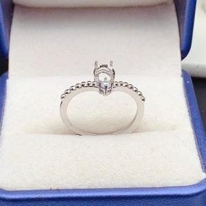 May include: A silver ring with a bezel setting for a round stone. The band is decorated with small beads.